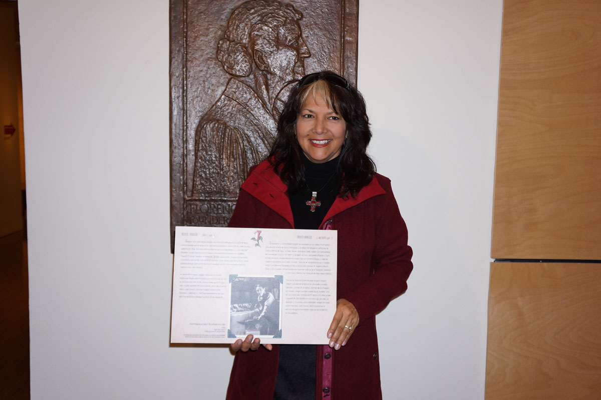 Debbie Brehm, granddaughter of woodcarver Moisés Aragón, with a text panel that honored Aragón in a 1999 museum exhibition